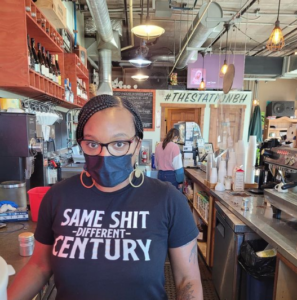 The Station's owner seen inside the coffe shop wearing a shirt that says 'same shit, different century'.