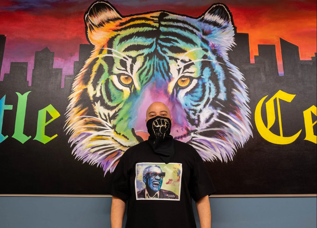Myron Curry in front of a mural of a tiger in rainbow colors